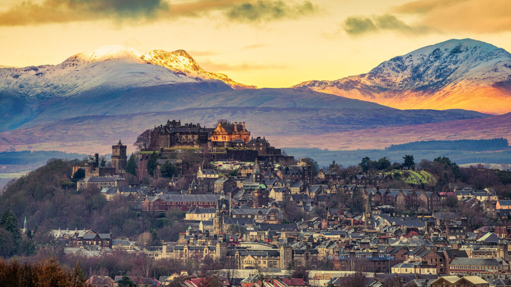 Stirling castle set against a dramatic backdrop of snow covered mountains